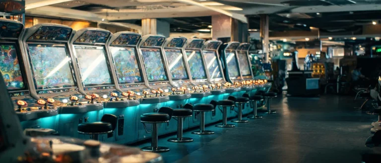 電子遊戲場內一整排弧形捕魚機台，檯面邊緣排列著圓形砲台按鈕